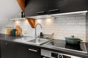 Cozinha moderna com armários pretos, pia de inox organizada e bancada escura com fogão de indução